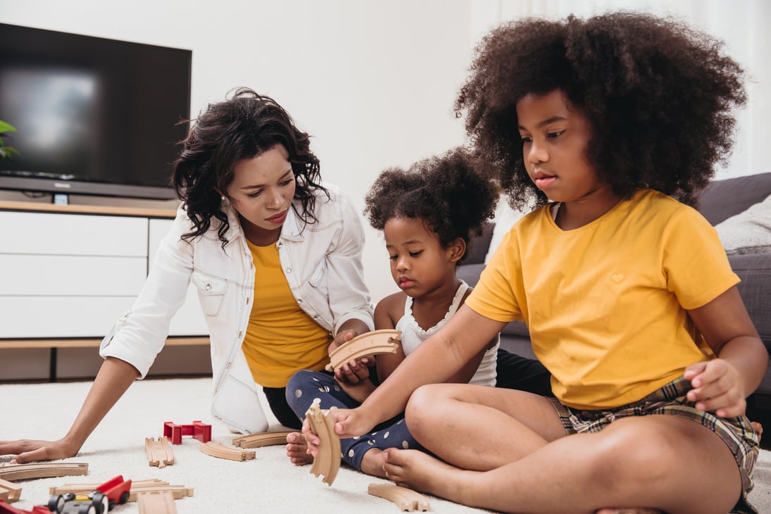 Nanny with Two Children Playing Toys in an Apartment